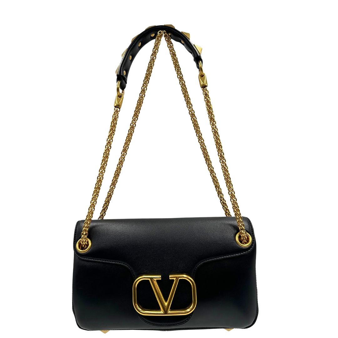 Front di una Borsa Stud Sign Valentino Garavani in pelle nera con parti metalliche dorate e tracolla in catena scorrevole con borchie piramidali dorate sullo spallaccio. Completa di dustbag e cartellino. Originale, usata, di lusso, in ottime condizioni