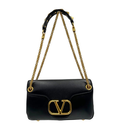 Front di una Borsa Stud Sign Valentino Garavani in pelle nera con parti metalliche dorate e tracolla in catena scorrevole con borchie piramidali dorate sullo spallaccio. Completa di dustbag e cartellino. Originale, usata, di lusso, in ottime condizioni