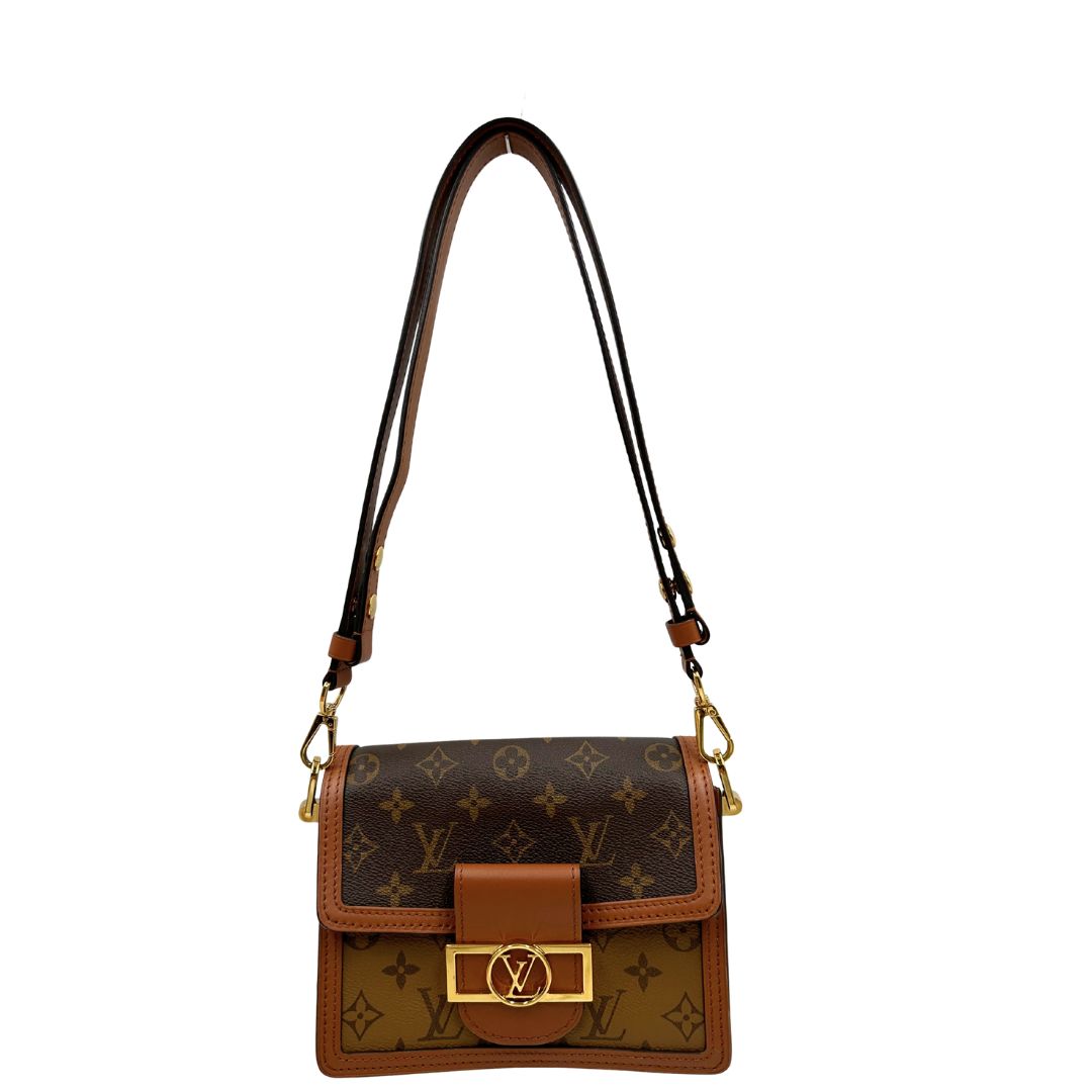 Front di una Borsa Dauphine Mini Louis Vuitton in tela monogram, e monogram reverse bicolore con finiture in pelle cognac e parti metalliche dorate, munita di una tracolla in pelle allungabile e un manico in catena, amovibili. Originale, usata, di lusso, in ottime condizioni