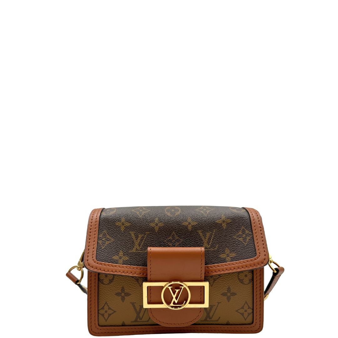 Front di una Borsa Dauphine Mini Louis Vuitton in tela monogram, e monogram reverse bicolore con finiture in pelle cognac e parti metalliche dorate, munita di una tracolla in pelle allungabile e un manico in catena, amovibili. Originale, usata, di lusso, in ottime condizioni