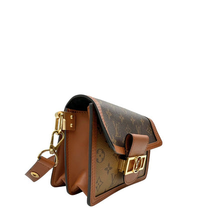 Lato destro di una Borsa Dauphine Mini Louis Vuitton in tela monogram, e monogram reverse bicolore con finiture in pelle cognac e parti metalliche dorate, munita di una tracolla in pelle allungabile e un manico in catena, amovibili. Originale, usata, di lusso, in ottime condizioni