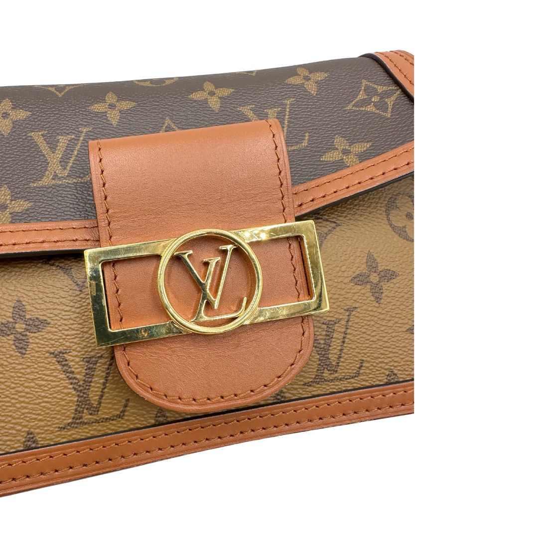 Chiusura di una Borsa Dauphine Mini Louis Vuitton in tela monogram, e monogram reverse bicolore con finiture in pelle cognac e parti metalliche dorate, munita di una tracolla in pelle allungabile e un manico in catena, amovibili. Originale, usata, di lusso, in ottime condizioni
