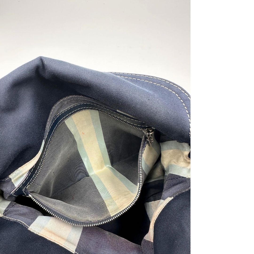 Interno di una borsa Fendi realizzata in tessuto blu navy con cuciture bianche a contrasto, manico leggermente regolabile e con parti metalliche argentate. Iconico logo effetto marble sulla chiusura della patta. Indossabile a spalla.