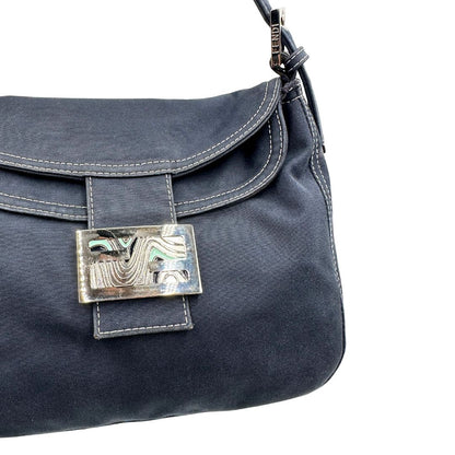 Chiusura di una borsa Fendi realizzata in tessuto blu navy con cuciture bianche a contrasto, manico leggermente regolabile e con parti metalliche argentate. Iconico logo effetto marble sulla chiusura della patta. Indossabile a spalla.