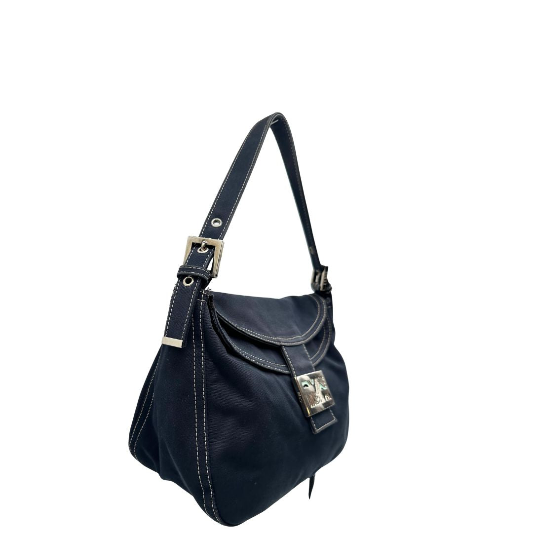 Laterale sinistro di una borsa Fendi realizzata in tessuto blu navy con cuciture bianche a contrasto, manico leggermente regolabile e con parti metalliche argentate. Iconico logo effetto marble sulla chiusura della patta. Indossabile a spalla.