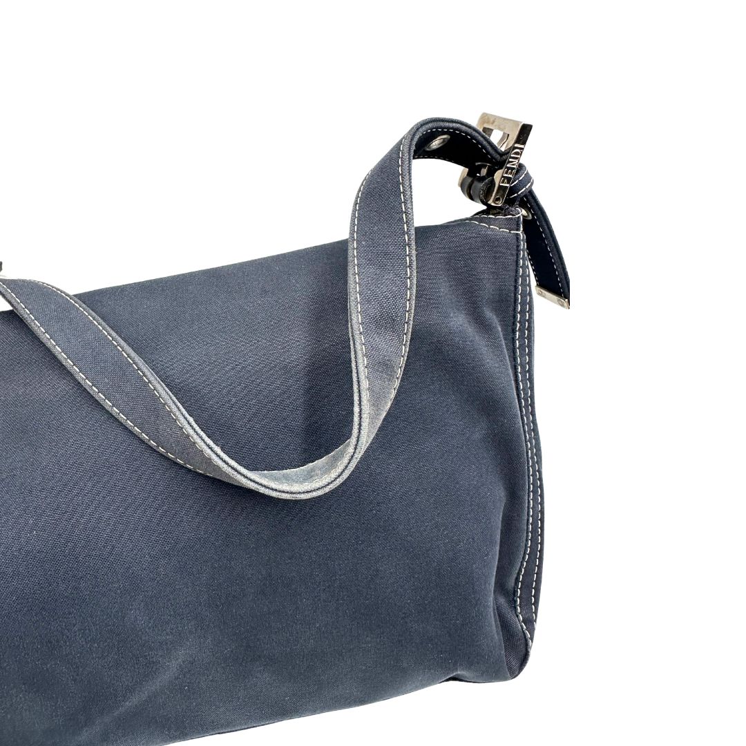 Difetto manico di una borsa Fendi realizzata in tessuto blu navy con cuciture bianche a contrasto, manico leggermente regolabile e con parti metalliche argentate. Iconico logo effetto marble sulla chiusura della patta. Indossabile a spalla.