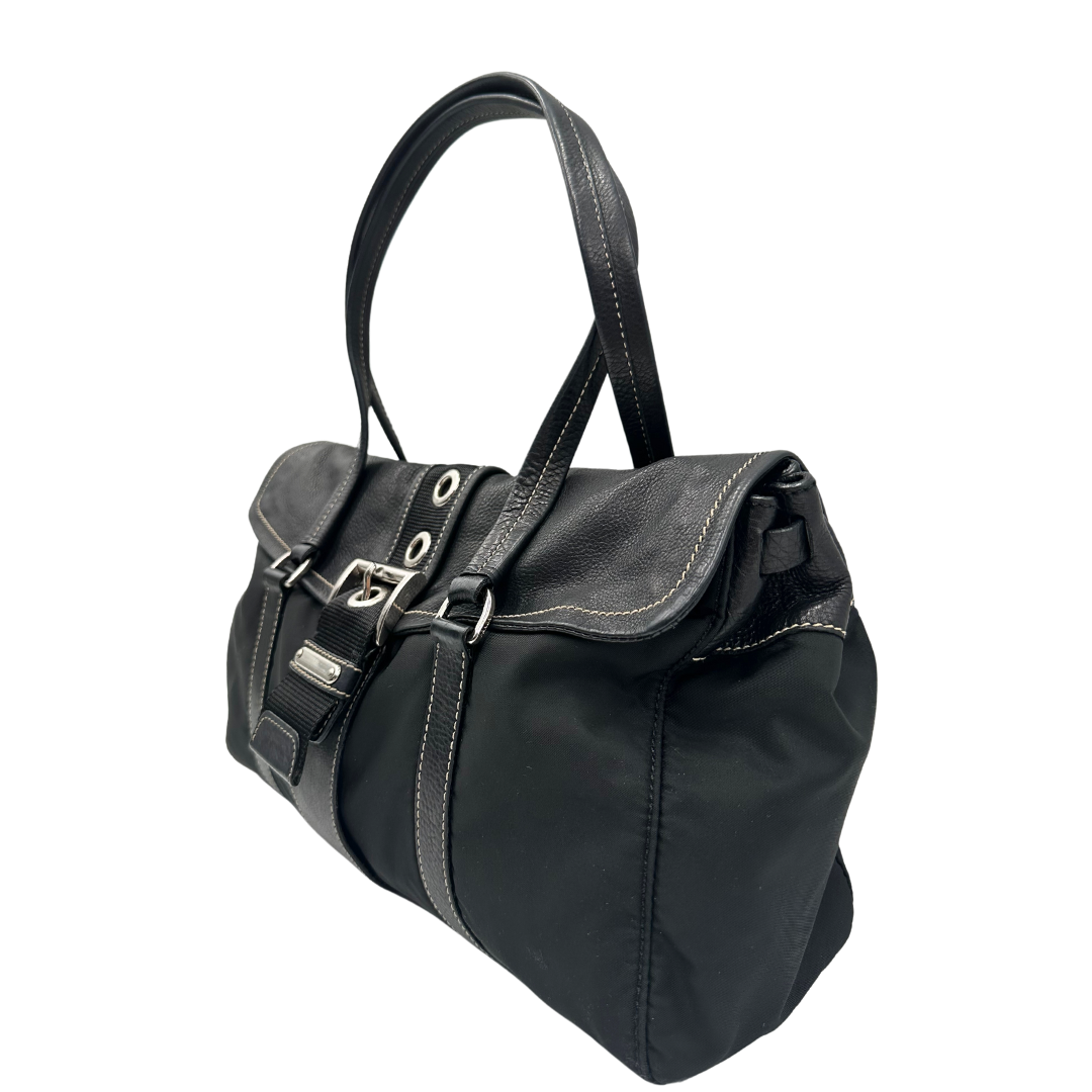 Borsa a spalla Prada in tessuto nero con dettagli in pelle e fibbia frontale argentata. Elegante e funzionale, perfetta per uno stile casual-chic.