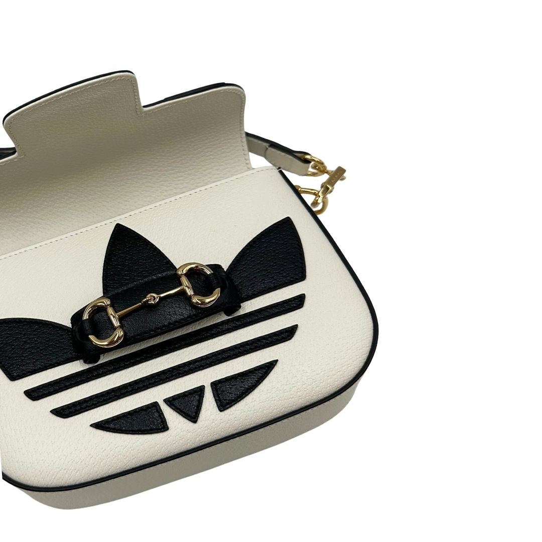Borsa Gucci x Adidas in pelle martellata bianca con logo Adidas e parti metalliche dorate, munita di una tracolla Web verde e rossa. Completa di corredo, di lusso, originale.
