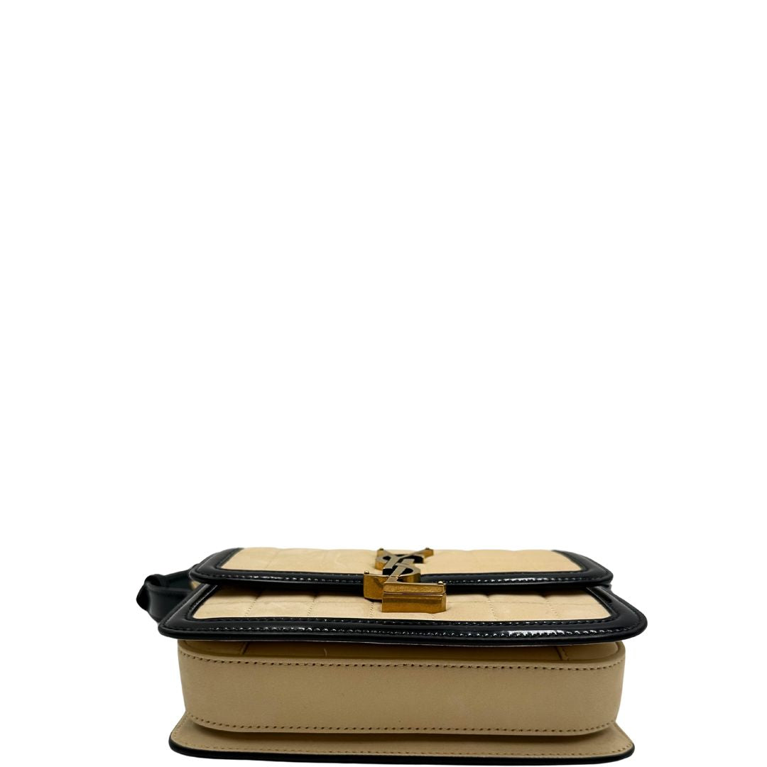 base Borsa Saint Laurent in pelle nabuk beige e pelle lucida nera con parti metalliche dorate, impreziosita da iconico logo Cassandre sul front; munita di un manico regolabile. Completa di corredo. 