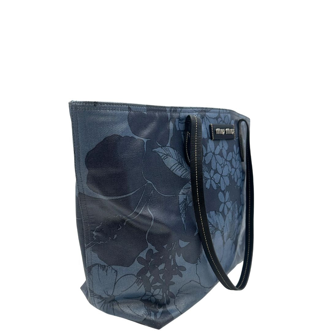 lato  Borsa Miu Miu in canvas sui toni del blu con trama floreale e parti metalliche argentate; munita di doppi manici. Completa di dustbag, di lusso, originale, usata. 