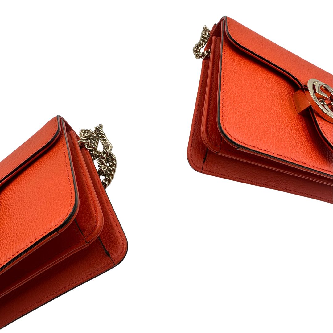 Angoli Borsa Gucci Interlocking in pelle martellata arancione con parti metalliche dorate. Munita di una tracolla scorrevole in catena e spallaccio. Rifinita con chiusura doppie G incrociate. Completa di dustbag. Originale, usato, in condizioni ottime. 