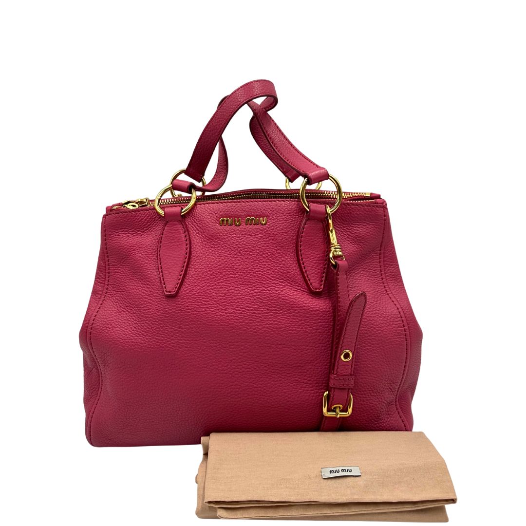 Borsa Miu Miu in pelle martellata color rosa orchidea con parti metalliche dorate; munita di doppi manici e una tracolla tracolla amovibile e regolabile. Completa di dustbag, di lusso, originale, ottime condizioni. 