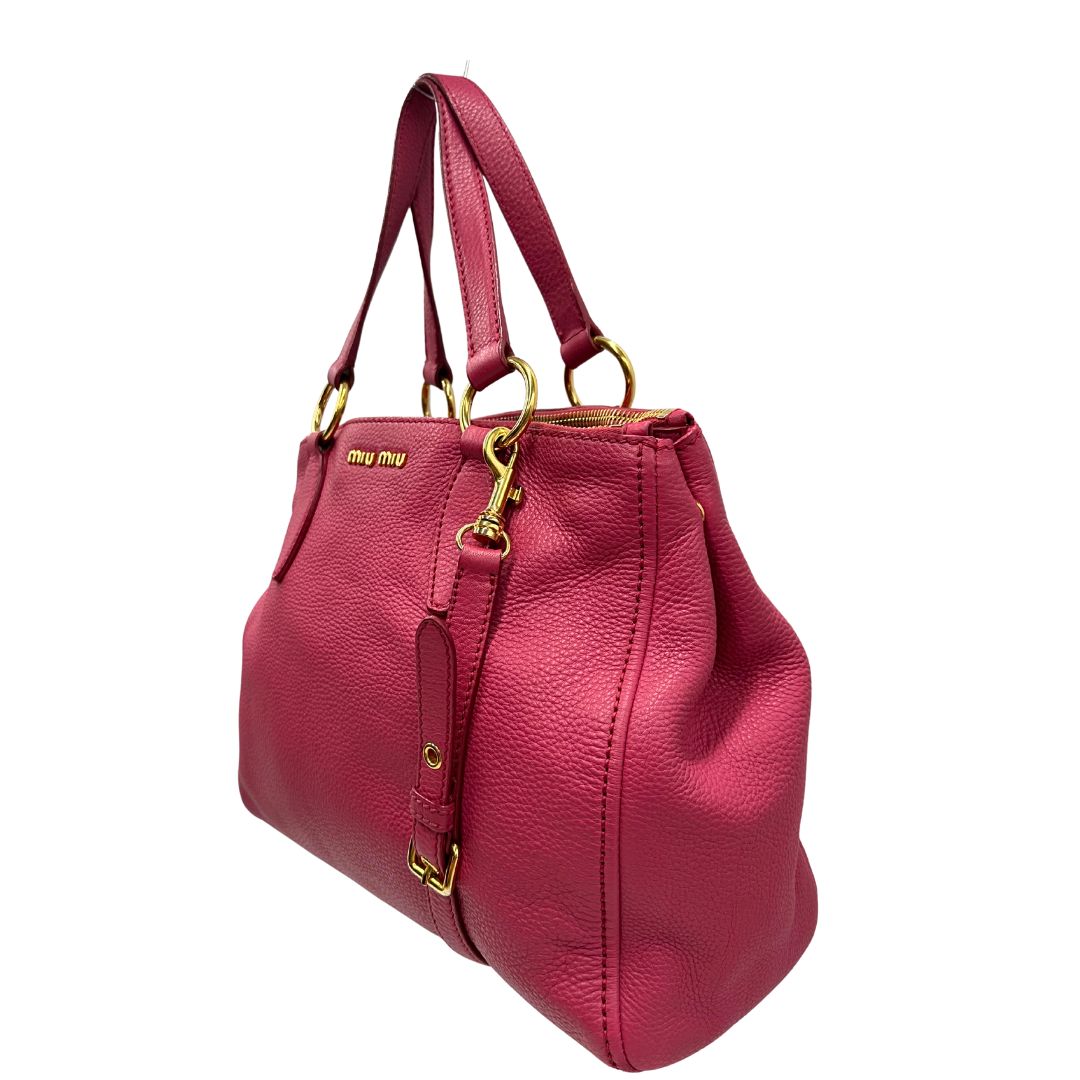 Borsa Miu Miu in pelle martellata color rosa orchidea con parti metalliche dorate; munita di doppi manici e una tracolla tracolla amovibile e regolabile. Completa di dustbag, di lusso, originale, ottime condizioni.
