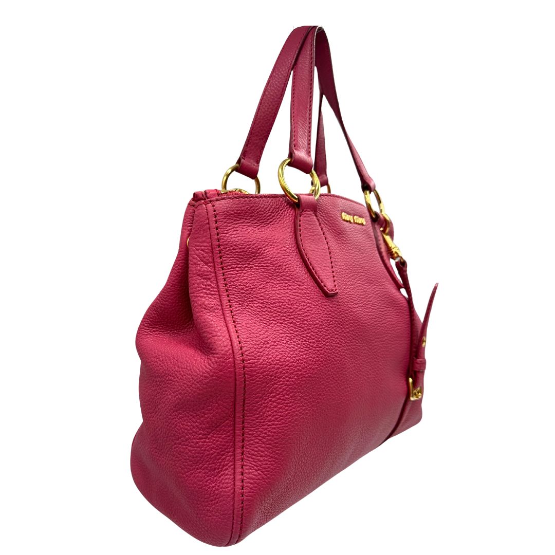 lato Borsa Miu Miu in pelle martellata color rosa orchidea con parti metalliche dorate; munita di doppi manici e una tracolla tracolla amovibile e regolabile. Completa di dustbag, di lusso, originale, ottime condizioni. 