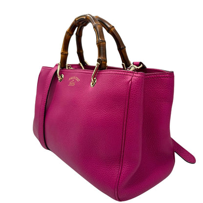 lato Borsa Gucci in pelle martellata fucsia con parti metalliche dorate; munita di doppi manici in bamboo e una tracolla amovibile e regolabile, di lusso, ottime condizioni, usata. 