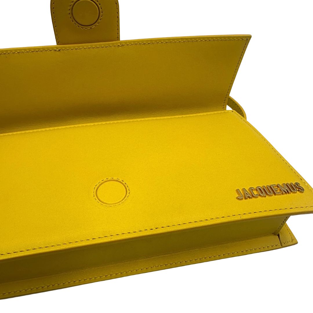 interno Borsa Jacquemus Le Bambino Long in pelle gialla con parti metalliche dorate; munita di un manico singolo. Completa di dustbag e cartellini, di lusso, originale, ottime condizioni.
