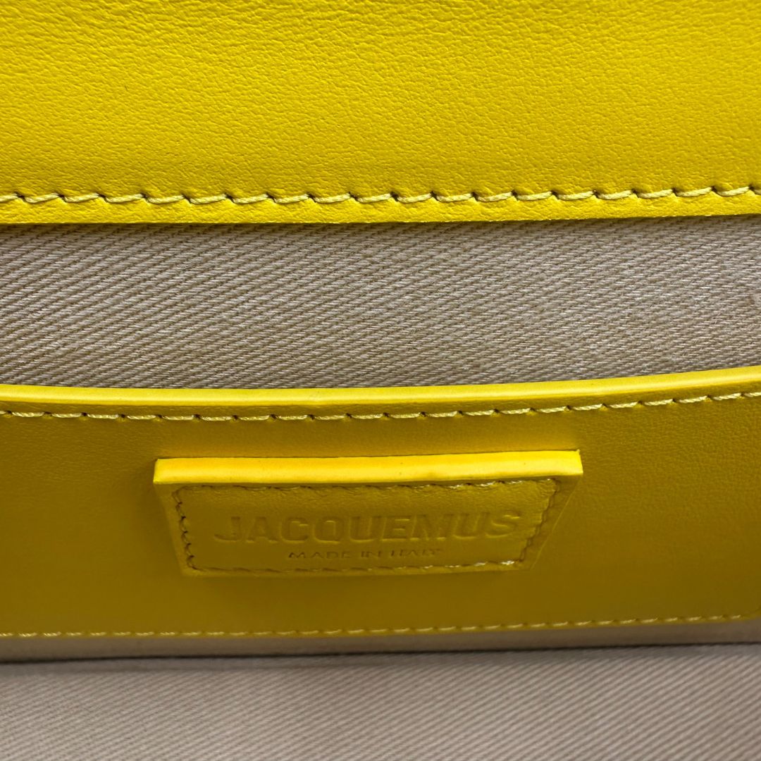 interno Borsa Jacquemus Le Bambino Long in pelle gialla con parti metalliche dorate; munita di un manico singolo. Completa di dustbag e cartellini, di lusso, originale, ottime condizioni.