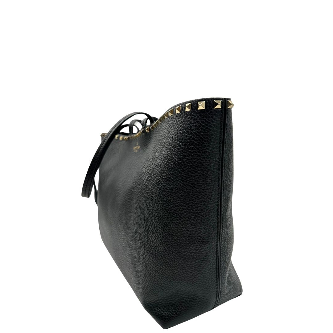 lato Borsa Valentino Garavani in pelle nera con parti metalliche dorate, impreziosita da borchie piramidali sulle finiture superiori; munita di doppi manici, di lusso, originale, ottimo stato. 