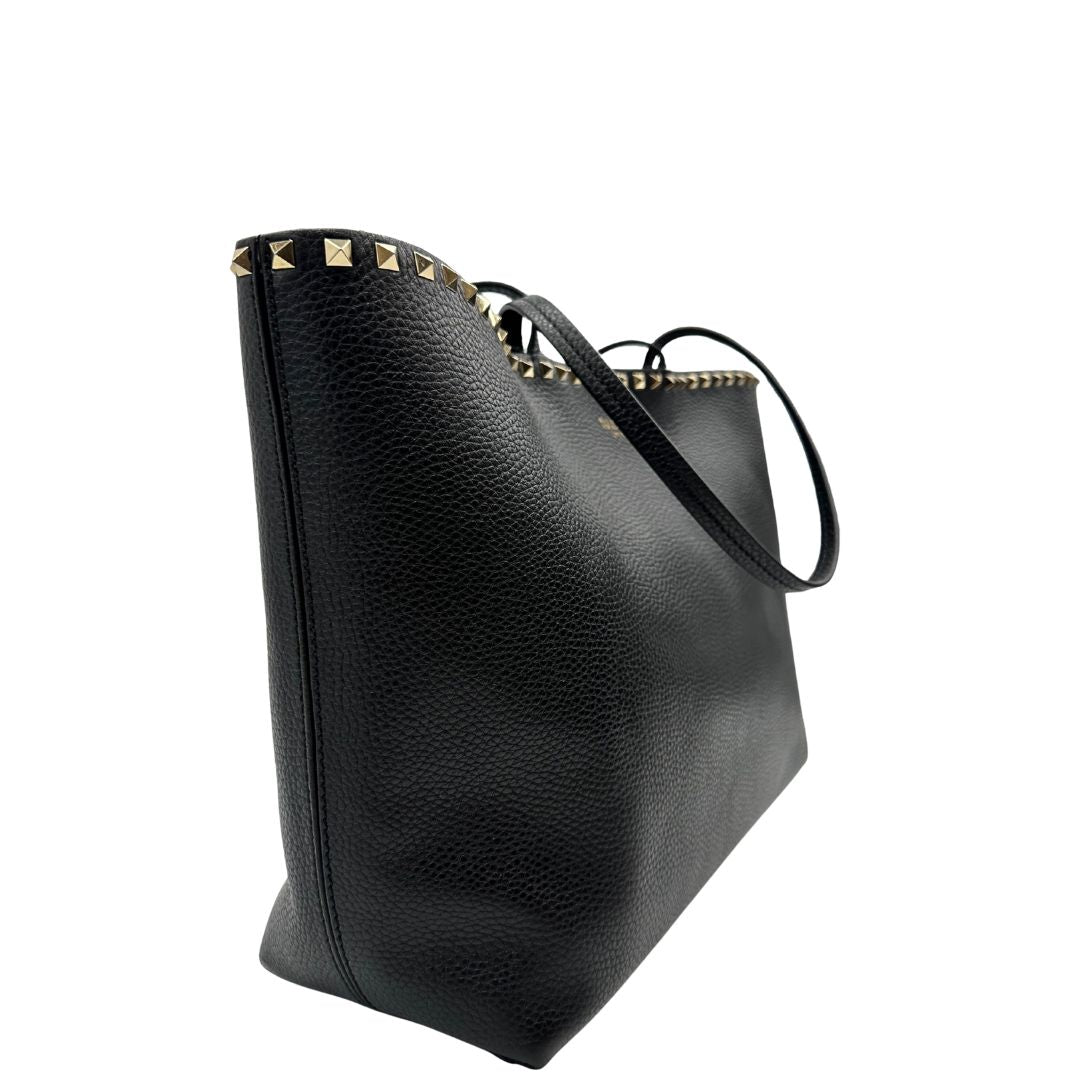 lato Borsa Valentino Garavani in pelle nera con parti metalliche dorate, impreziosita da borchie piramidali sulle finiture superiori; munita di doppi manici, di lusso, originale, ottimo stato. 