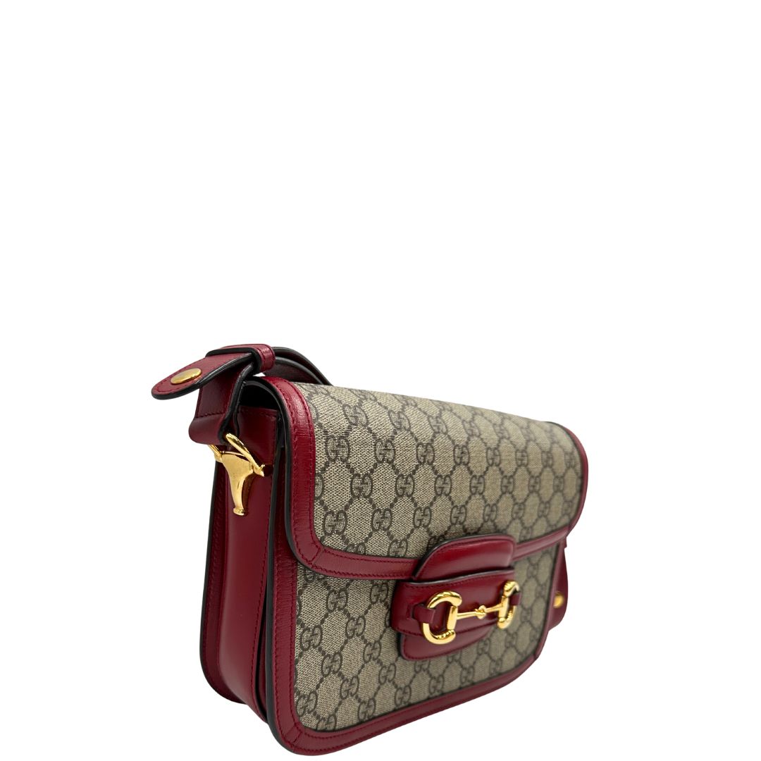 lato Borsa Gucci Horsebit 1955 in canvas beige GG con finiture in pelle bordeaux e parti metalliche dorate. Munita di un manico leggermente allungabile e rifinita con iconico morsetto Horsebit sulla chiusura. Completa di dustbag, di lusso, originale, ottime condizioni, usata. 
