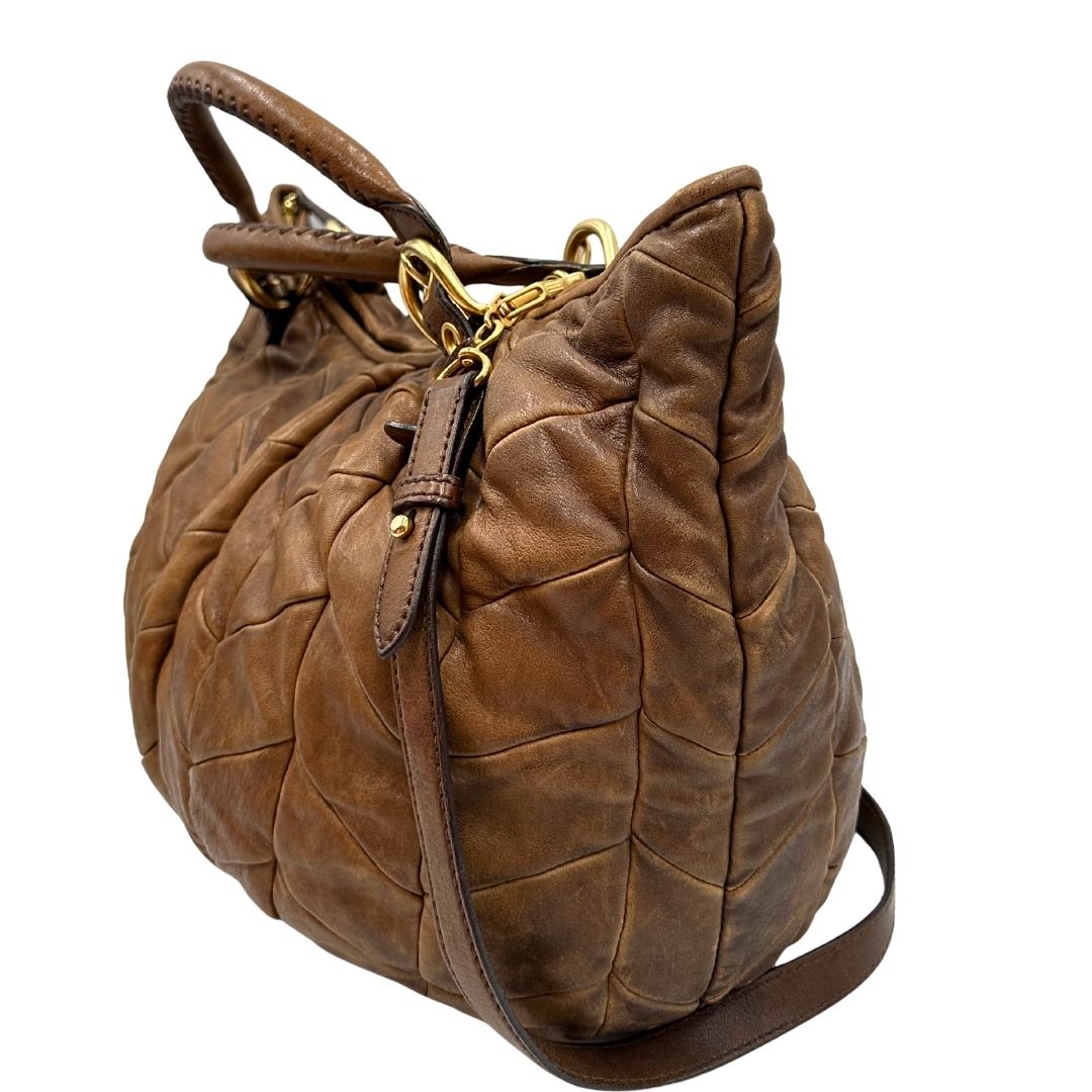 lato Borsa Miu Miu in pelle color cammello con parti metalliche dorate; munita di un manico singolo e una tracolla amovibile, di lusso, usata, originale, ottime condizioni. 