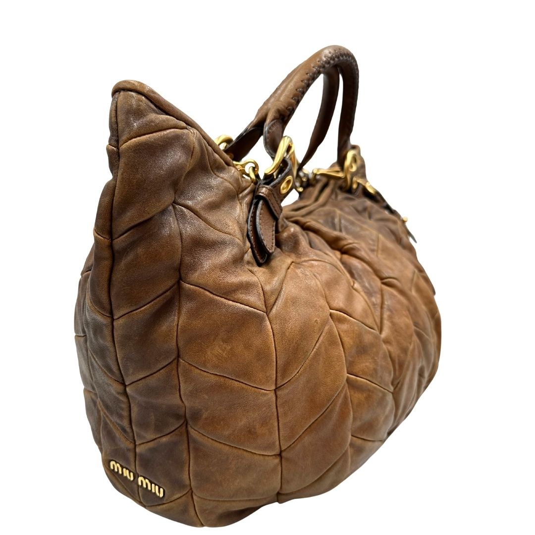 lato Borsa Miu Miu in pelle color cammello con parti metalliche dorate; munita di un manico singolo e una tracolla amovibile, di lusso, usata, originale, ottime condizioni. 