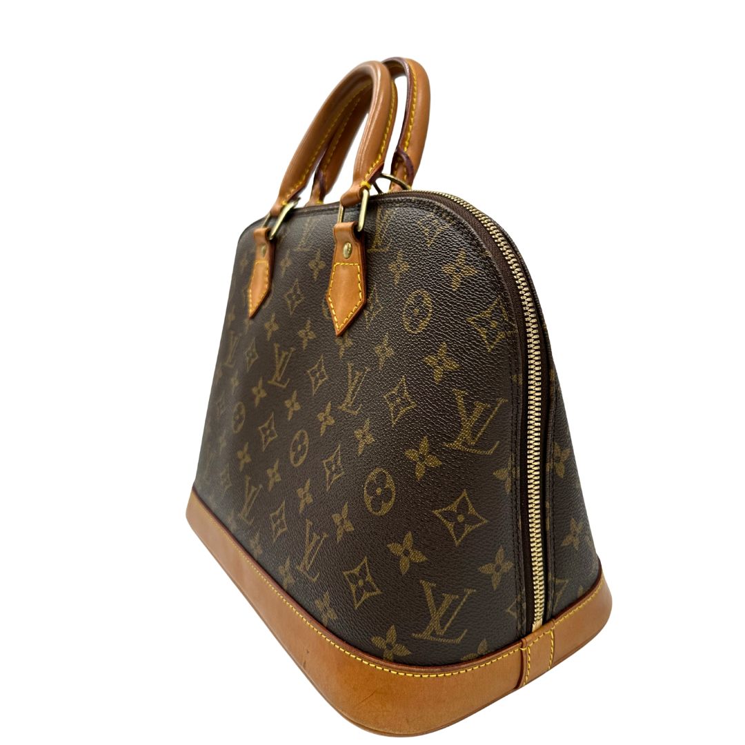 lato Borsa Louis Vuitton in canvas marrone monogram con finiture in vacchetta naturale e parti metalliche dorate; munita di doppi manici stondati, da portare a mano. Completa di chiavi e lucchetto, di lusso, originale, ottime condizioni. 