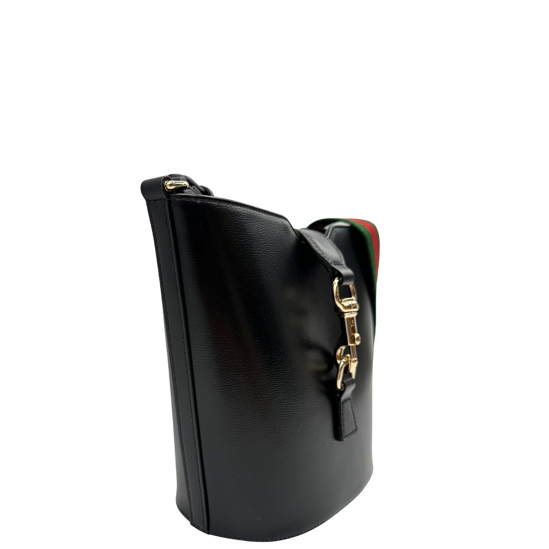 lato Mini bucket Gucci in pelle nera con parti metalliche dorate; munito di una tracolla in tessuto Web verde e rossa. Completo di dustbag, di lusso, eccellenti condizioni, originale, usato. 