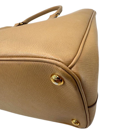 angoli  Borsa Prada in pelle saffiano color nocciola con parti metalliche dorate; munita di doppi manici stondati e impreziosita da una clochette portachiavi. Completa di dustbag, di lusso, originale, buone condizioni. 