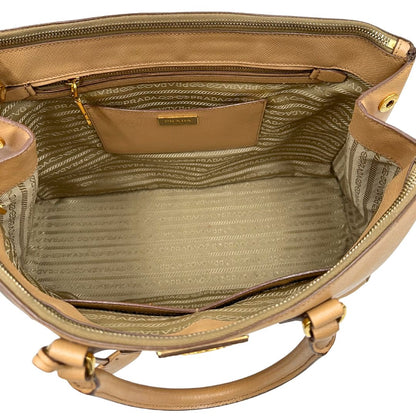 interno  Borsa Prada in pelle saffiano color nocciola con parti metalliche dorate; munita di doppi manici stondati e impreziosita da una clochette portachiavi. Completa di dustbag, di lusso, originale, buone condizioni. 