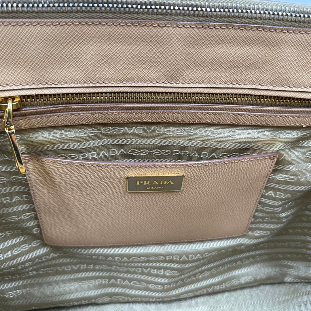 interno  Borsa Prada in pelle saffiano color nocciola con parti metalliche dorate; munita di doppi manici stondati e impreziosita da una clochette portachiavi. Completa di dustbag, di lusso, originale, buone condizioni. 