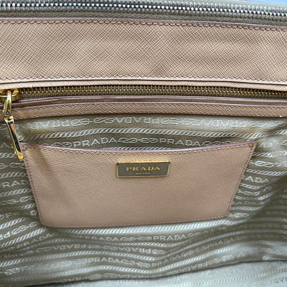 interno  Borsa Prada in pelle saffiano color nocciola con parti metalliche dorate; munita di doppi manici stondati e impreziosita da una clochette portachiavi. Completa di dustbag, di lusso, originale, buone condizioni. 