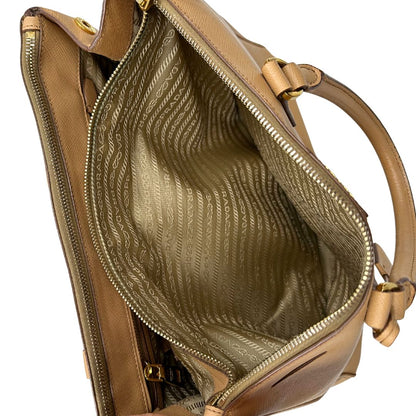 interno  Borsa Prada in pelle saffiano color nocciola con parti metalliche dorate; munita di doppi manici stondati e impreziosita da una clochette portachiavi. Completa di dustbag, di lusso, originale, buone condizioni. 