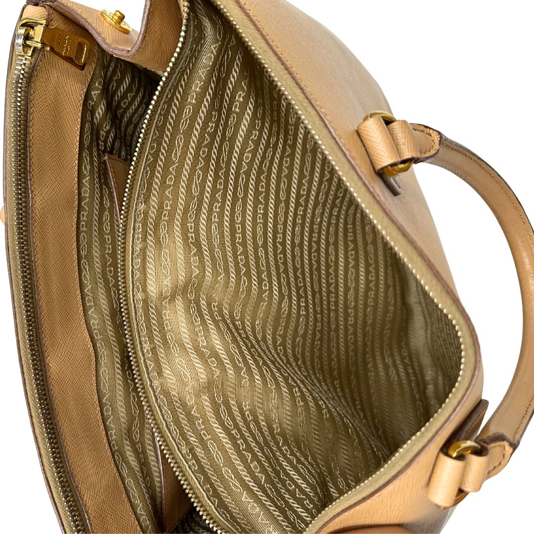 interno  Borsa Prada in pelle saffiano color nocciola con parti metalliche dorate; munita di doppi manici stondati e impreziosita da una clochette portachiavi. Completa di dustbag, di lusso, originale, buone condizioni. 