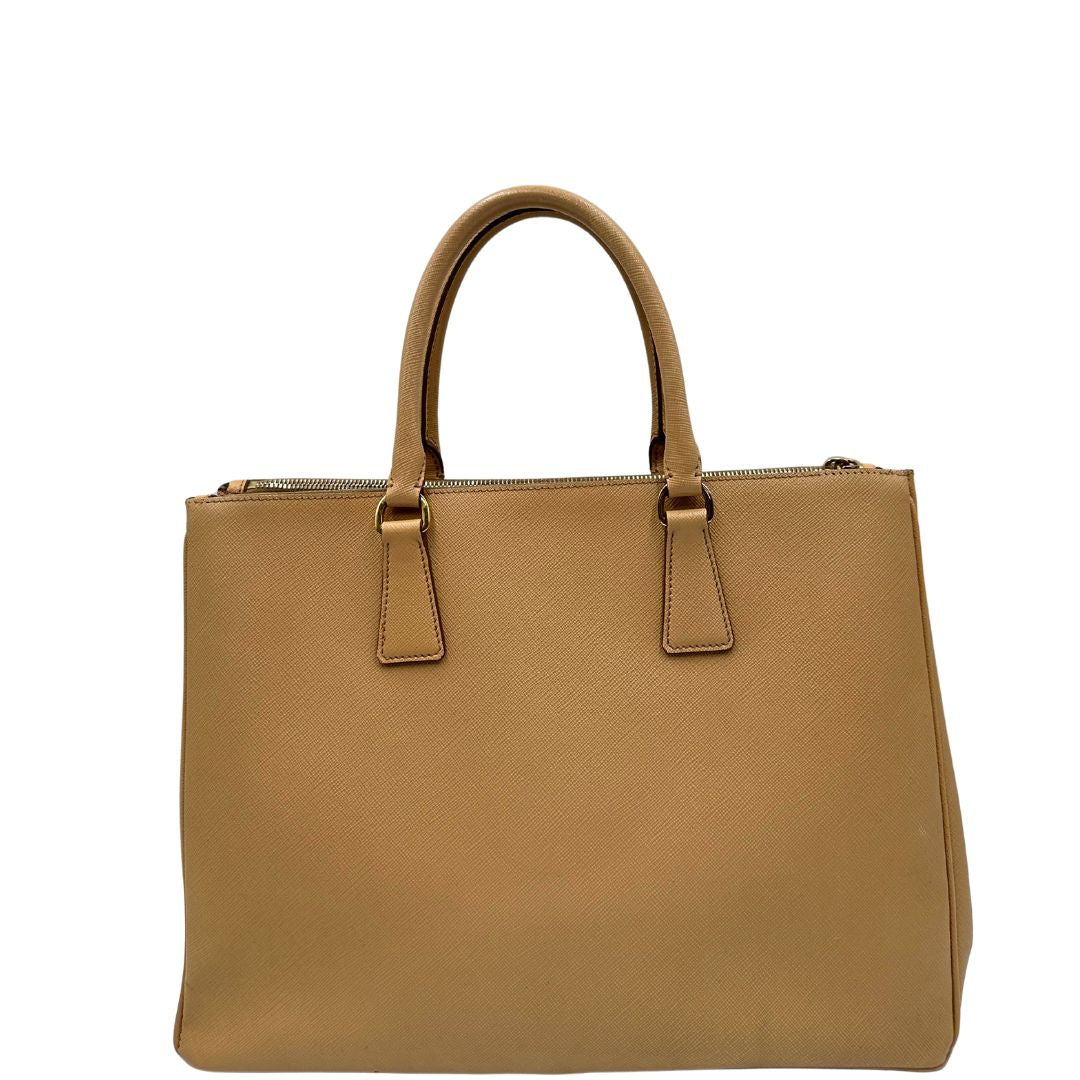 retro  Borsa Prada in pelle saffiano color nocciola con parti metalliche dorate; munita di doppi manici stondati e impreziosita da una clochette portachiavi. Completa di dustbag, di lusso, originale, buone condizioni. 