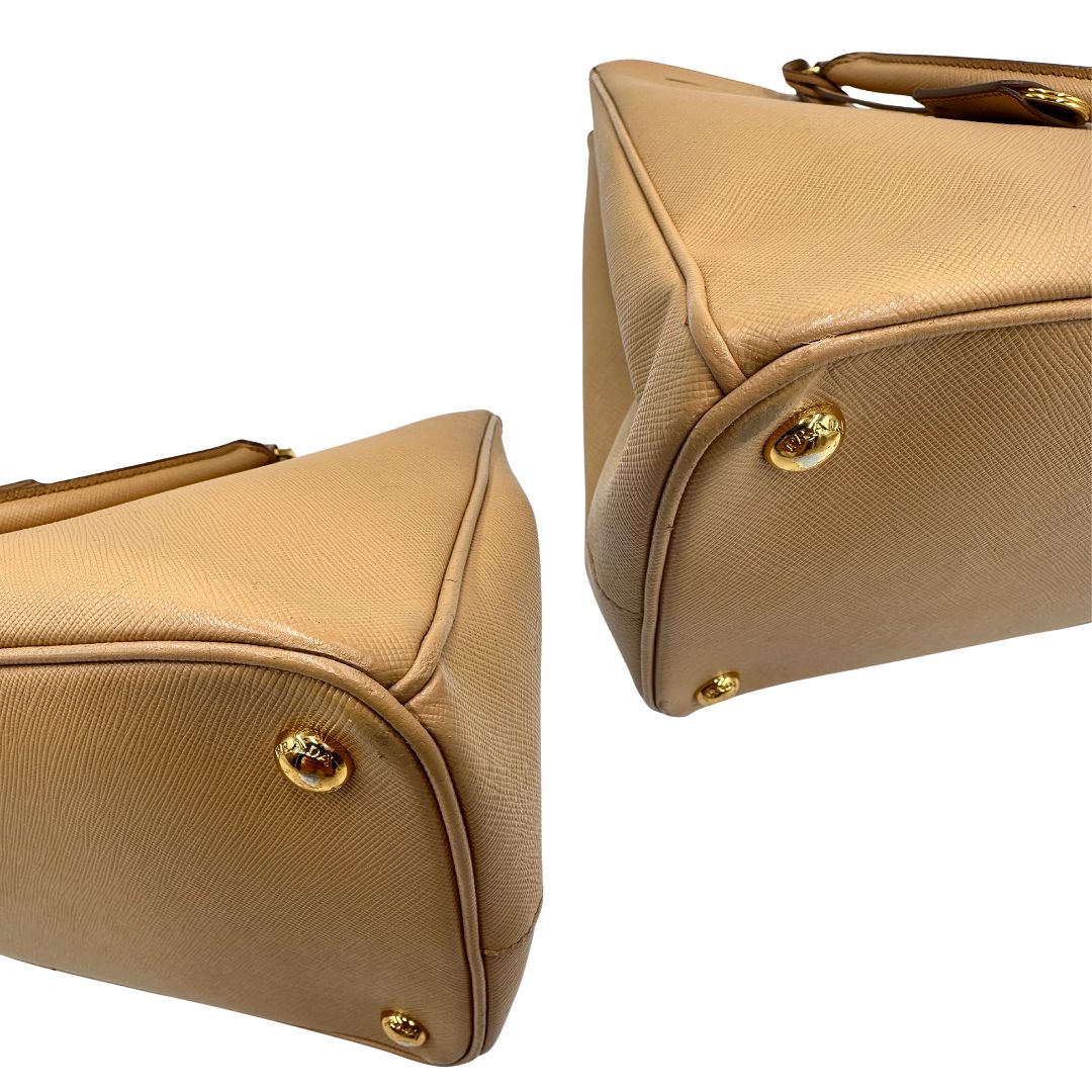 angoli  Borsa Prada in pelle saffiano color nocciola con parti metalliche dorate; munita di doppi manici stondati e impreziosita da una clochette portachiavi. Completa di dustbag, di lusso, originale, buone condizioni. 