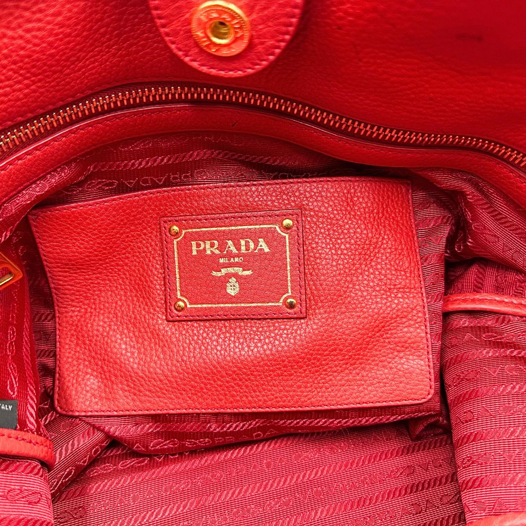 interno Borsa Tote Prada in pelle rossa con parti metalliche dorate; munita di doppi manici e una tracolla amovibile e regolabile, di lusso, originale, ottime condizioni, usata. 