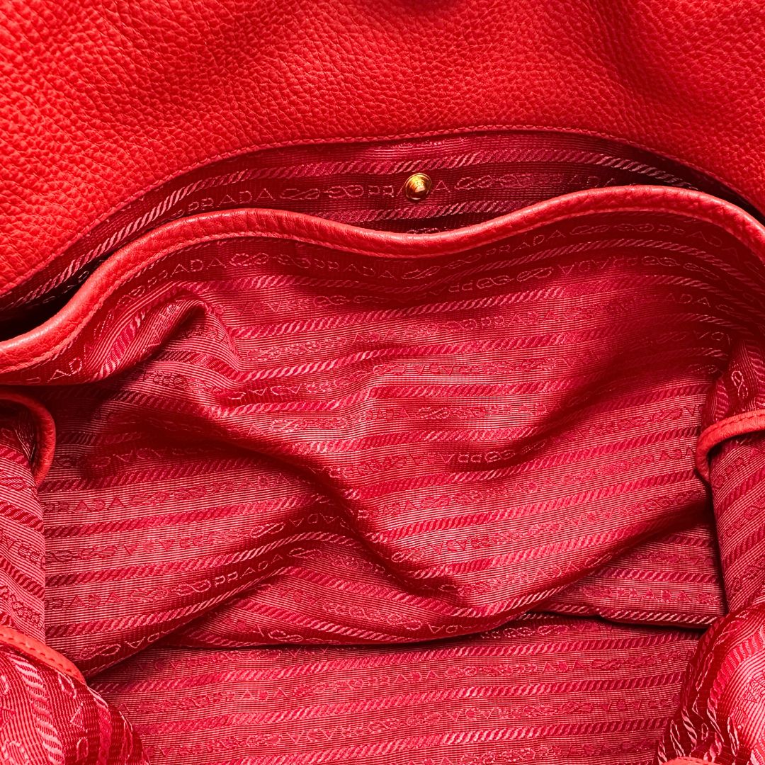 interno Borsa Tote Prada in pelle rossa con parti metalliche dorate; munita di doppi manici e una tracolla amovibile e regolabile, di lusso, originale, ottime condizioni, usata. 