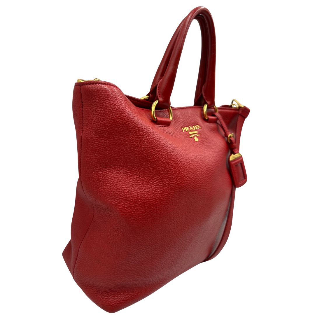 lato Borsa Tote Prada in pelle rossa con parti metalliche dorate; munita di doppi manici e una tracolla amovibile e regolabile, di lusso, originale, ottime condizioni, usata. 