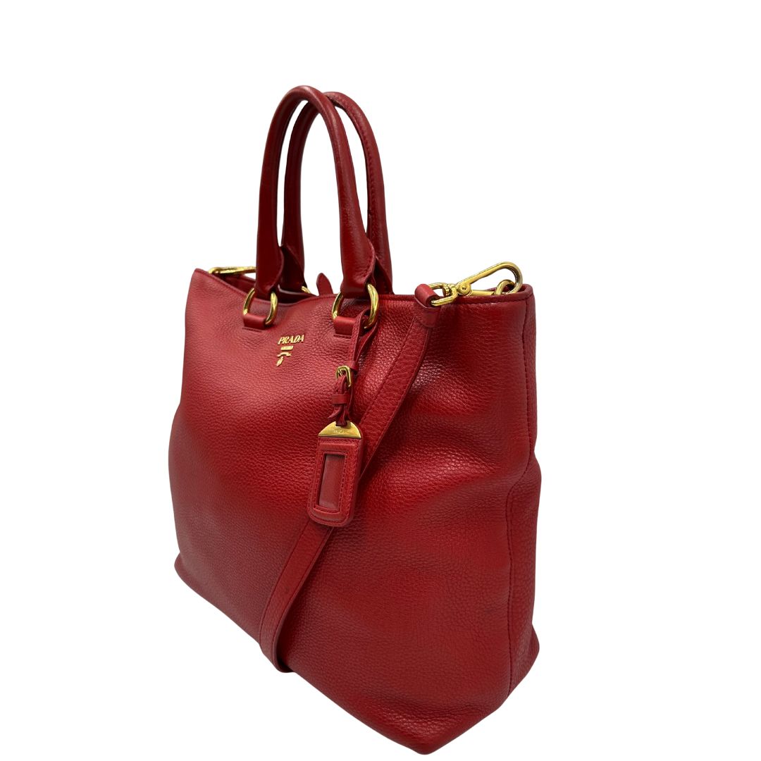 lato Borsa Tote Prada in pelle rossa con parti metalliche dorate; munita di doppi manici e una tracolla amovibile e regolabile, di lusso, originale, ottime condizioni, usata. 