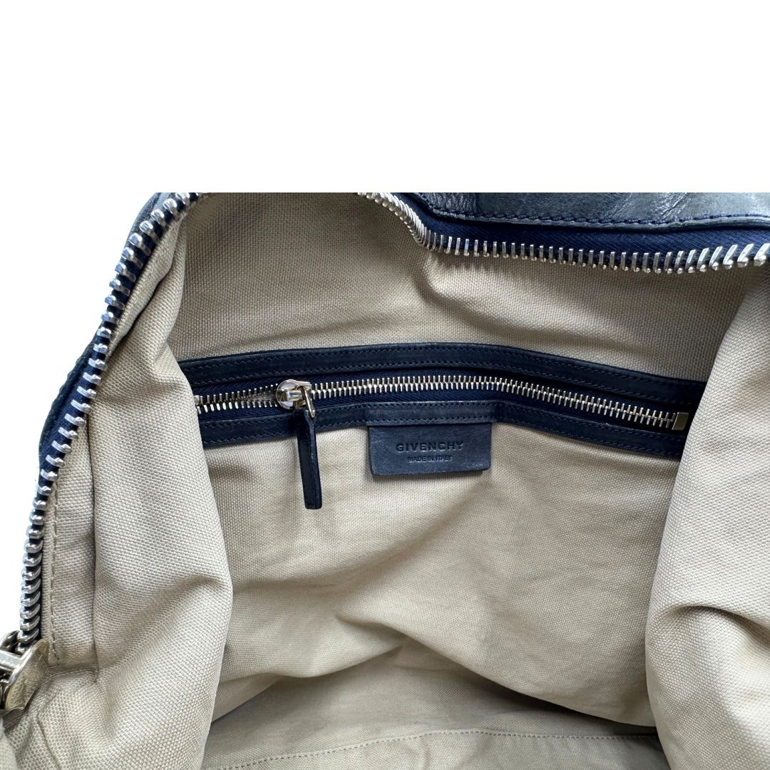 Tasca interna di una Borsa Givenchy Nightingale in pelle blu notte e parti metalliche dorate. Munita di doppi manici e tracolla una amovibile arricchita da una cerniera decorativa. Indossabile a mano o a tracolla. Originale, usata, di lusso, in ottime condizioni