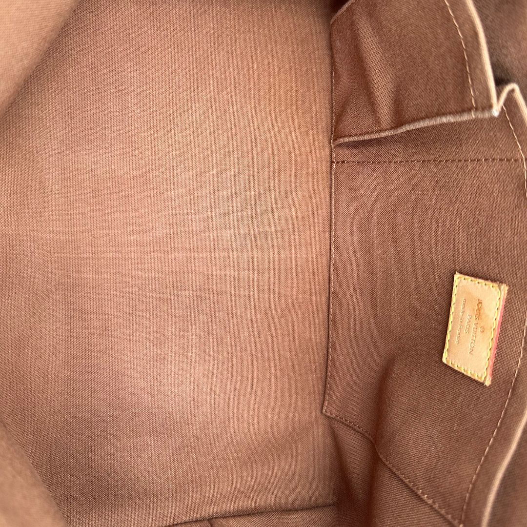 Interno di una borsa Louis Vuitton in canvas marrone monogram con cuciture decorative e finiture in vacchetta naturale. Parti metalliche dorate; munita di doppi manici, indossabile a spalla.