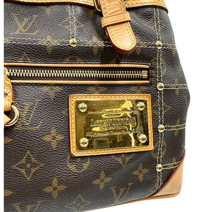 Dettaglio metallico di una borsa Louis Vuitton in canvas marrone monogram con cuciture decorative e finiture in vacchetta naturale. Parti metalliche dorate; munita di doppi manici, indossabile a spalla.