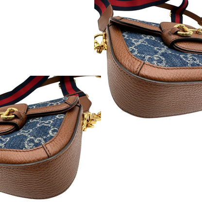 angoli Borsa Gucci in tessuto effetto denim con trama GG , finiture in pelle marroni e parti metalliche dorate; munita di una tracolla Web in tessuto blu e rossa e una tracolla in pelle, entrambe amovibili e regolabili. Completa di dustbag, di lusso, originale, eccellenti condizioni. 