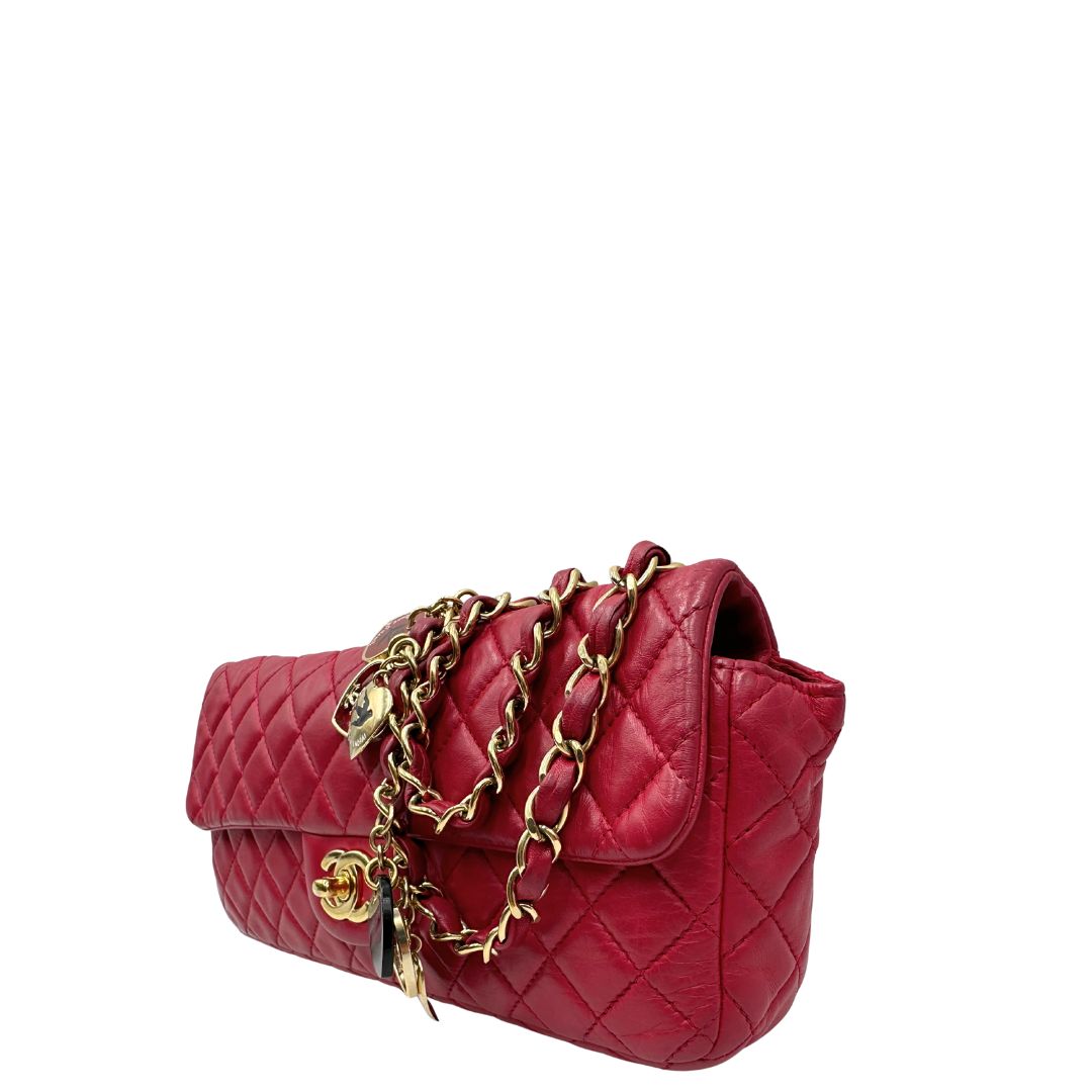 Lato sinistro di una Borsa Chanel Gabrielle in pelle matelassé color fucsia con parti metalliche dorate; impreziosita da charm con cuoricini sulla tracolla intrecciata in catena e pelle. Completa di scatola e card di autenticità. Originale, usata, di lusso in ottime condizioni