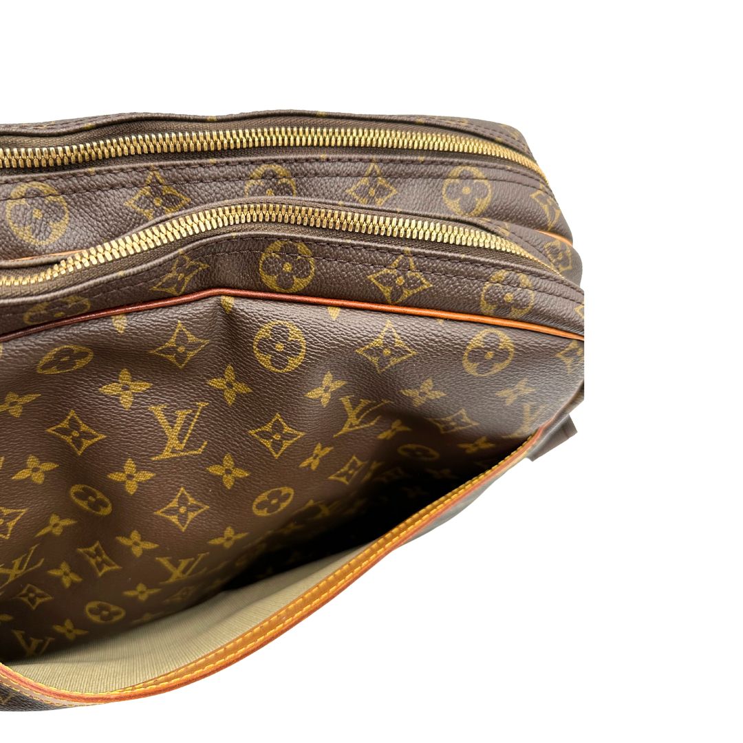Tasca esterna di una Borsa LV in canvas marrone monogram con finiture in vacchetta naturale e metalleria dorata, munita di una tracolla in tessuto regolabile. Completa di dustbag, lucchetti e chiavi. Originale, usata, di lusso, in ottime condizioni