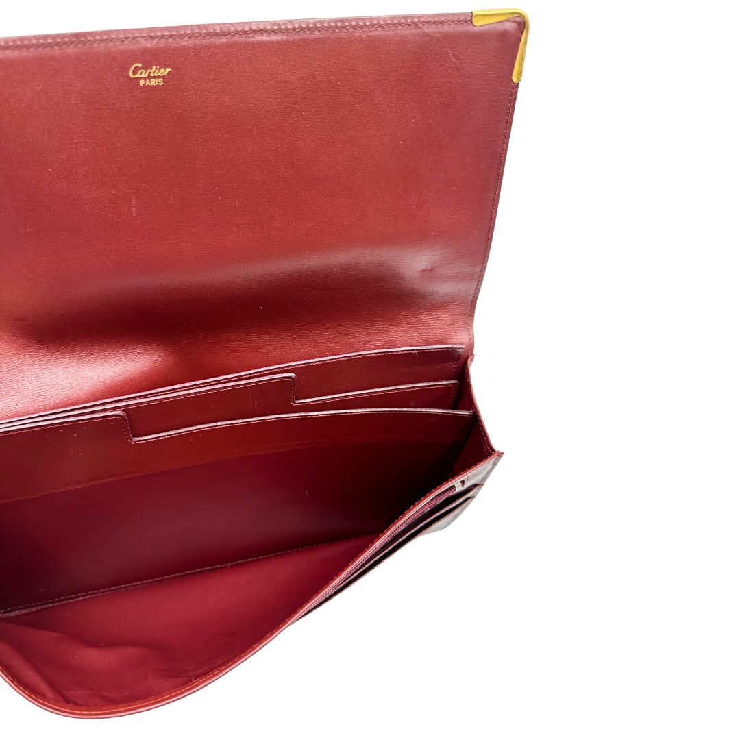 interni  Clutch Les Must de Cartier in pelle bordeaux con parti metalliche dorate. Munito di scatola, di lusso, originale.