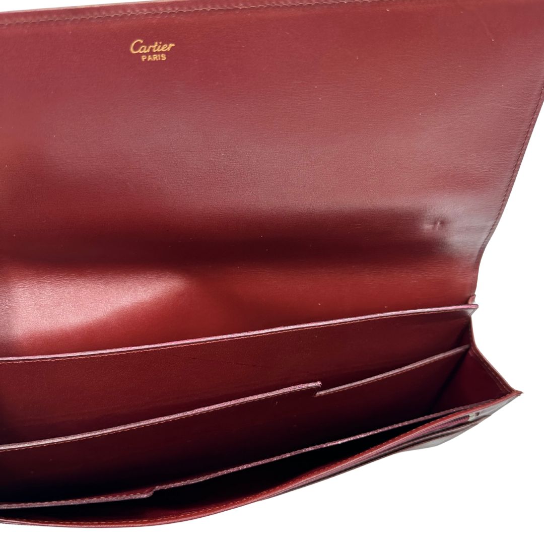 interni  Clutch Les Must de Cartier in pelle bordeaux con parti metalliche dorate. Munito di scatola, di lusso, originale.