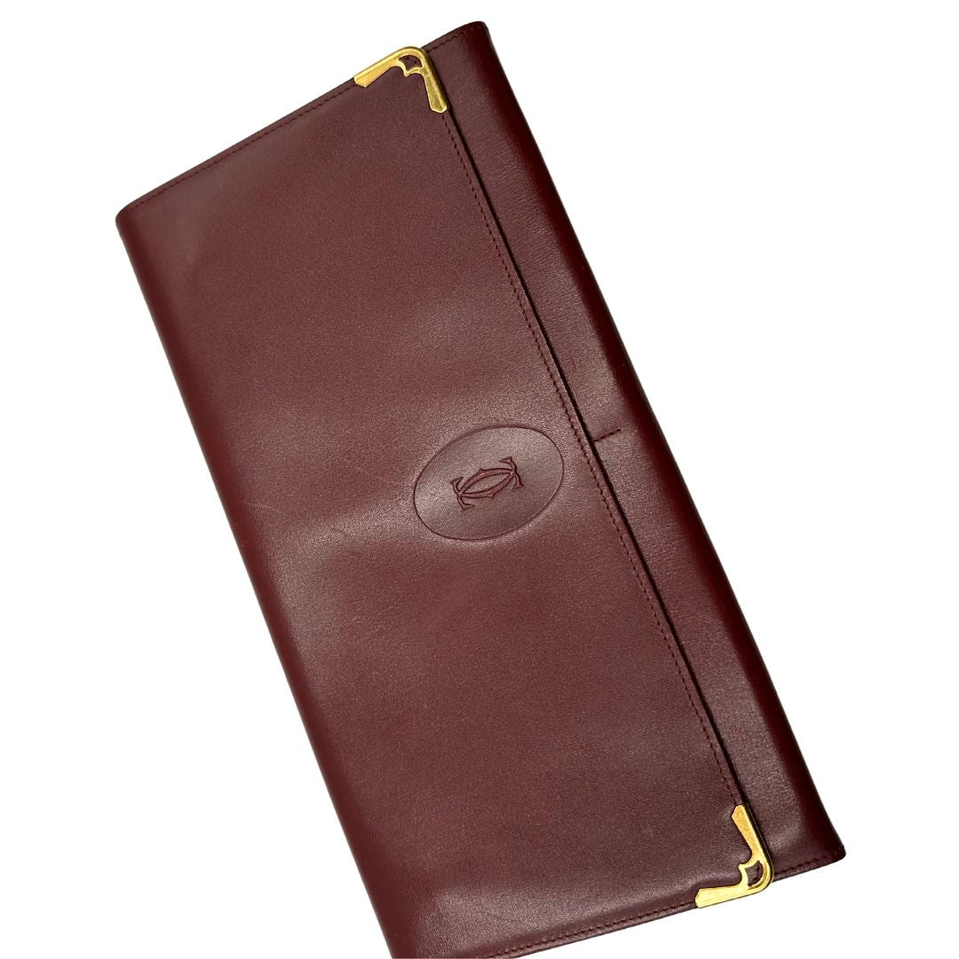  Clutch Les Must de Cartier in pelle bordeaux con parti metalliche dorate. Munito di scatola, di lusso, originale.
