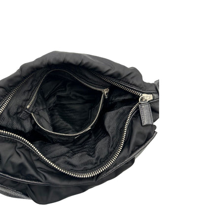 Interno di una Borsa Prada in nylon nero con parti metalliche argentate e dettagli in pelle tono su tono. Munita di una tracolla regolabile con fibbie, rifinita con logo triangolare sul lato destro. Originale, usata, di lusso, in condizioni buone.